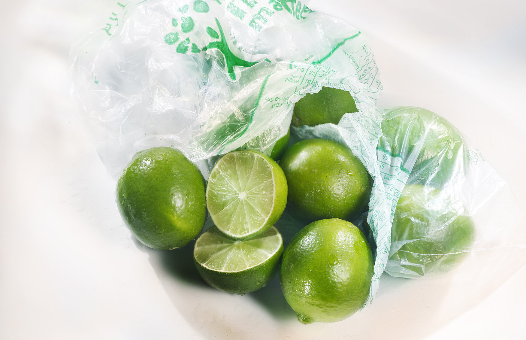 whole fresh green Limes in supermarket plastic bag with signature lighting