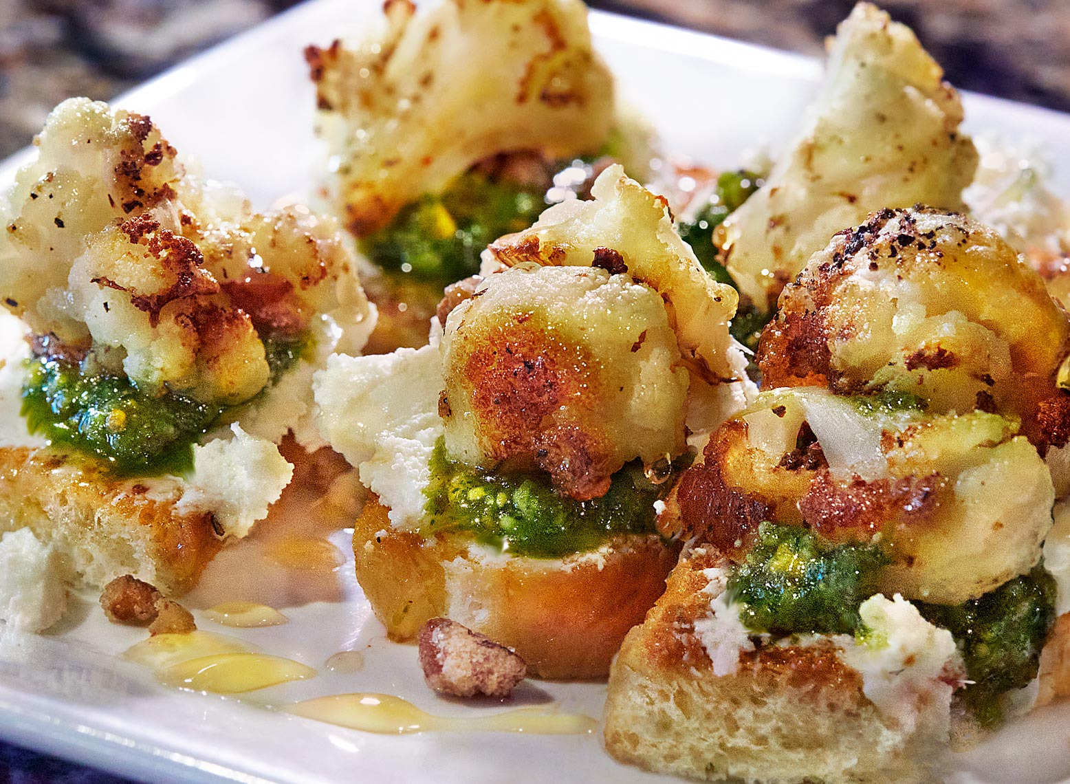 Pan roasted cauliflower seasoned with fresh herbs and sea salt, served on grilled focaccia crostini, whipped goat cheese, pistachio pesto, candied nuts and local honey at The Chef and I restaurant in Nashville Tennessee