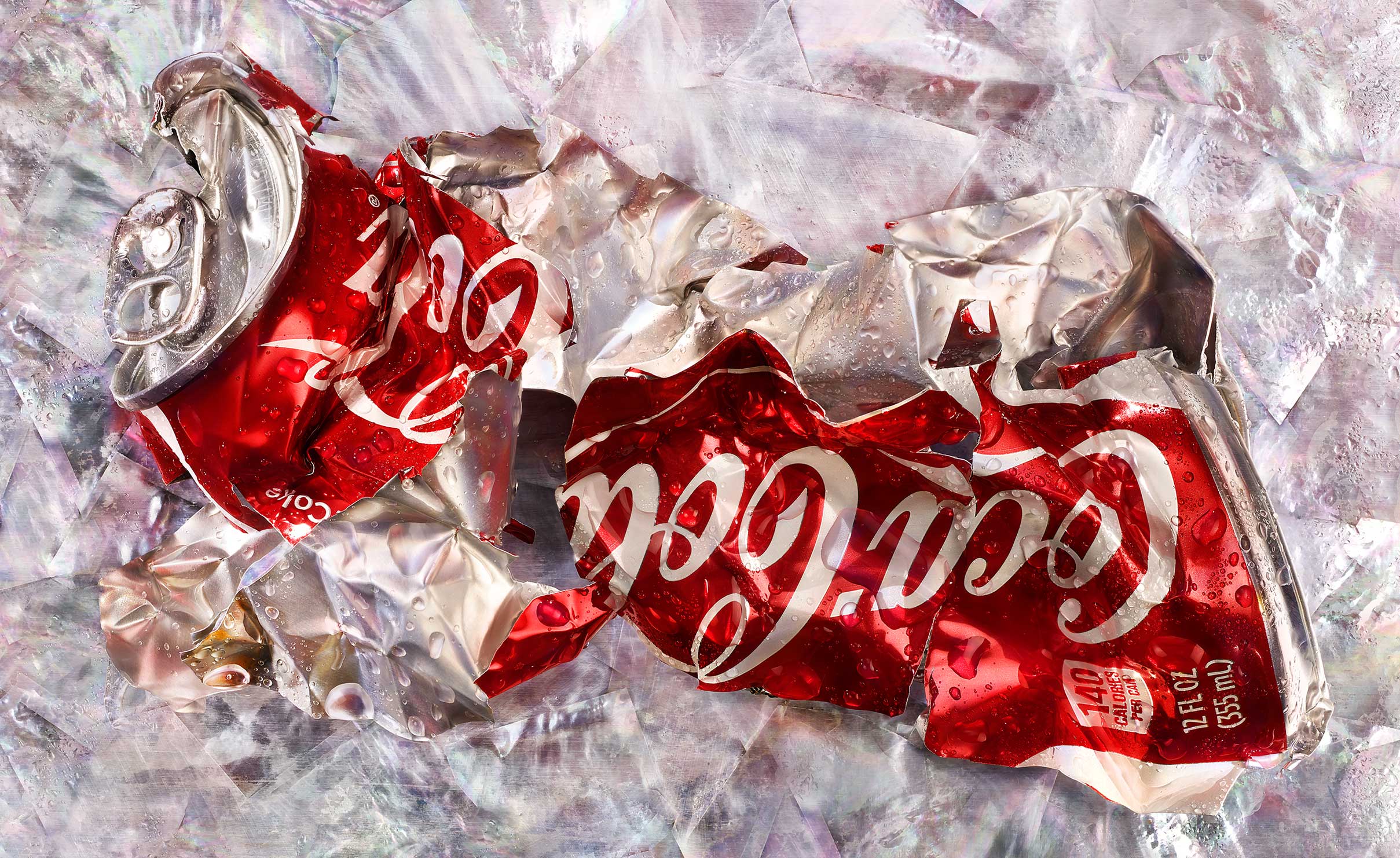 One crushed red and silver Coke aluminum metal soda can on metallic background
