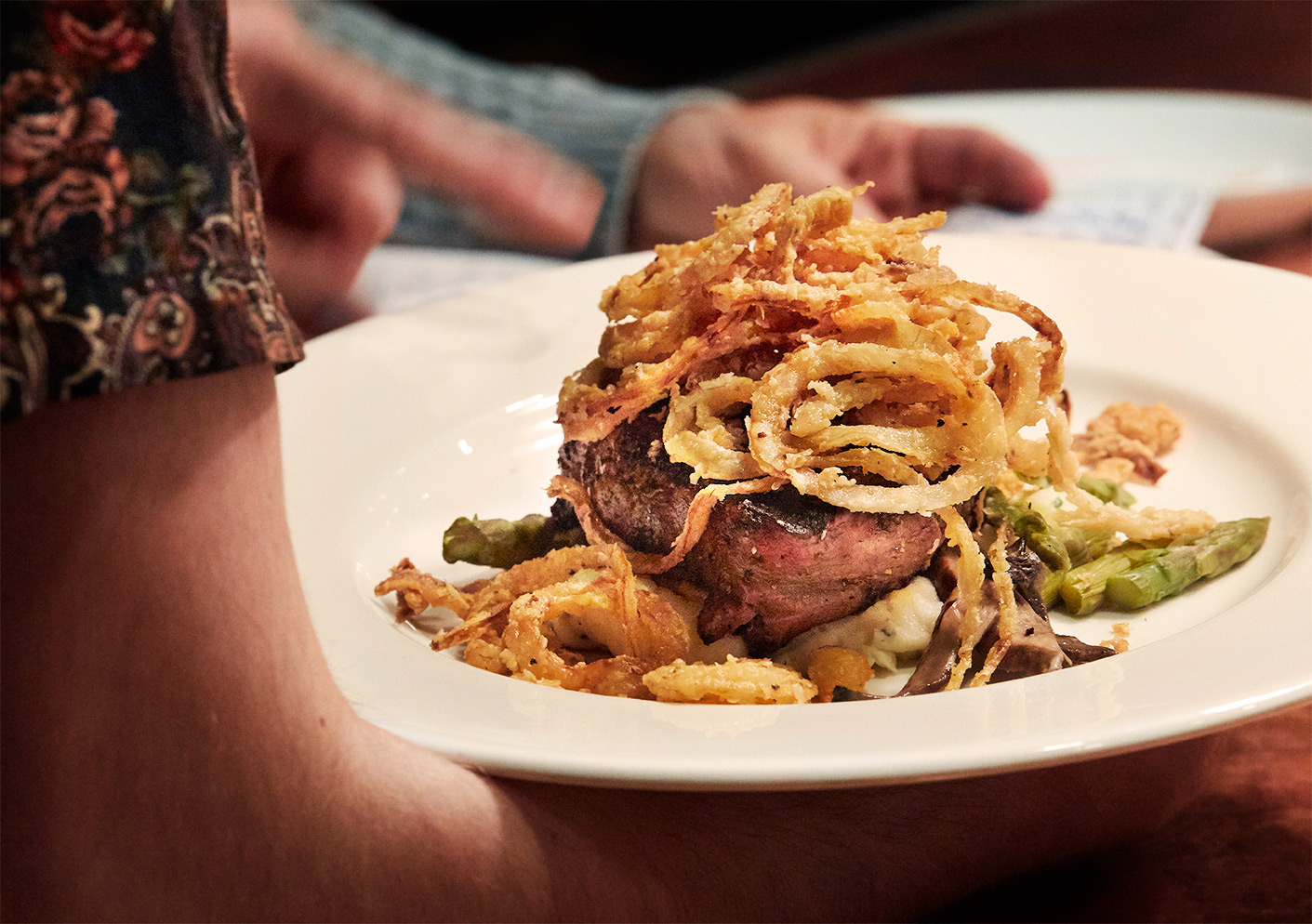 Steak and Onion Rings carried by a waiter at The Southern Steak and Oyster Restaurant in Nashville